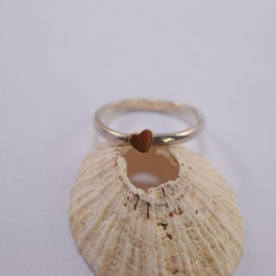 R18. silver ring with tiny gold heart